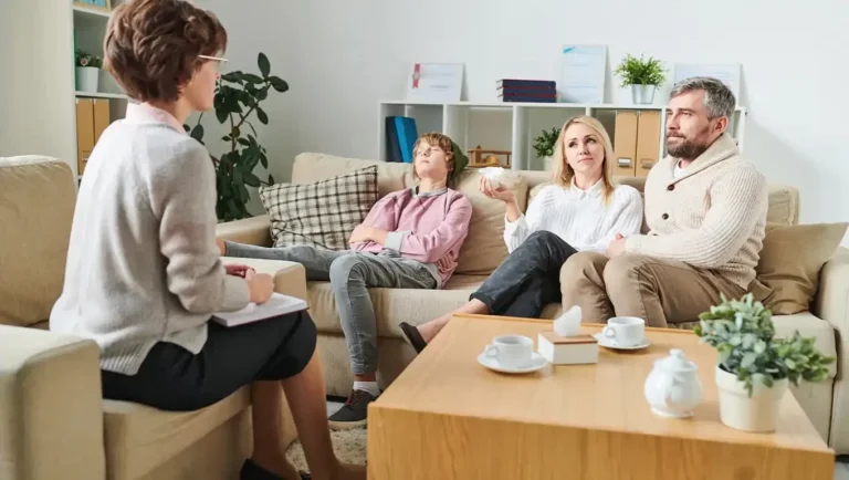 A therapist counsels a family with a reluctant teenage son during a therapy session.